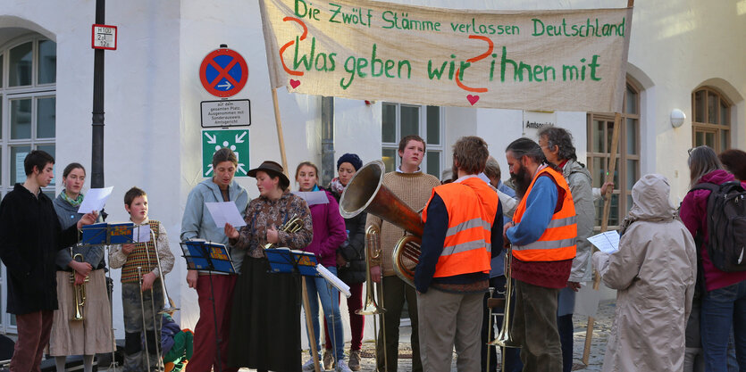 Menschen stehen mit einem Plakat auf einer Straße.