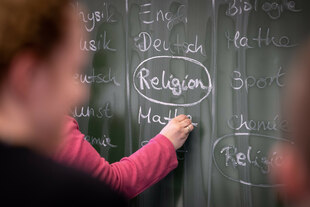 An einer Schultafel hat eine Lehrkraft den Eintrag Religion im Stundenplan umkringelt An einer Schultafel hat eine Lehrkraft den Eintrag Religion im Stundenplan umkringelt
