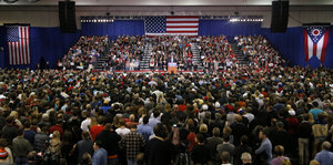Ein Raum mit vielen Menschen, auf der Bühne Donald Trump, aber nur klein zu sehen