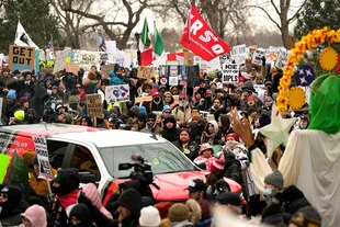 Demonstranten versammeln sich während einer Kundgebung für Nicole Good - sie tragen viele Schilder und Transparente gegen die ICE
