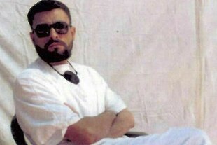 Porträt von Abu Subaida, er trägt eine Sonnenbrille und sitzt auf einem Stuhl