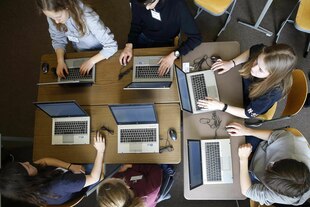 Schüler sitzen vor Laptop und Smartboard Schüler sitzen vor Laptop und Smartboard