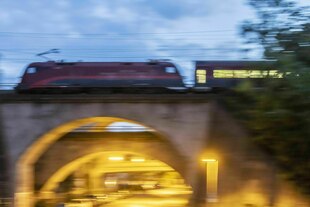 Ein Zug fährt in Dunkelheit über eine Brücke