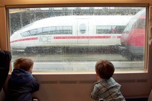 Zwei Kinder betrachten aus einem Zugfenster einen ICE