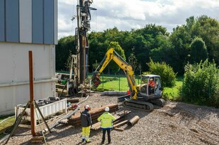 Ein Bagger an einer Baustelle mit einem Bohrloch Ein Bagger an einer Baustelle mit einem Bohrloch