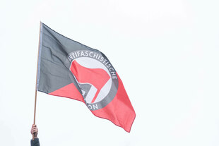 Eine Hand hält eine Fahne der Antifaschistischen Aktion