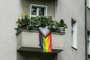 Eine Regenbogenfahne hängt am balkon eines Berliner Wohnhauses