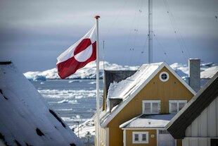 Eine grönländische Fahne zwischen traditionellen Holzhäusern