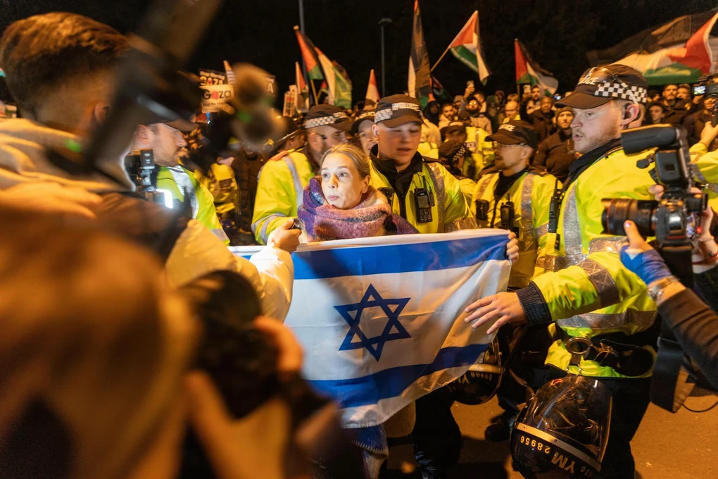 Eine britische Pro-Israel-Demonstrantin, die eine Flagge Israels vor sich hält, wird vor dem Euro-League-Spiel Aston Villa vs. Maccabi Tel Aviv von der Polizei geschützt