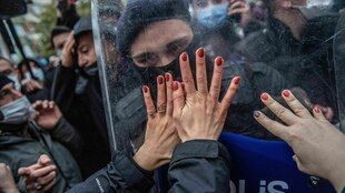 Frauenhände stemmen sich gegen das Visier eines Polizisten