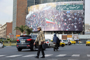 Eine Straßenszene in Teheran mit einem riesigen Propagandaplakat an einem Haus