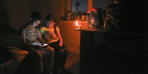 Zwei junge TartarInnen spielen bei Kerzenlicht auf der von Russland annektierten Halbinsel Krim mit ihrem Handy.