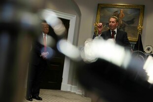 Zwei Männer stehen in einem Raum, ein Gemälde ist im Hintergrund zu sehen Zwei Männer stehen in einem Raum, ein Gemälde ist im Hintergrund zu sehen