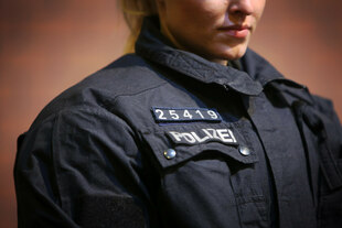 Nahaufnahme einer Person in Polizeiuniform. Im Fokus steht der Brustbereich, an dem ein Klettstreifen mit der weißen Aufschrift „POLIZEI“ sowie darüber ein kleinerer Patch mit der fünfstelligen Ziffernfolge „25419“ befestigt ist. Nahaufnahme einer Person in Polizeiuniform. Im Fokus steht der Brustbereich, an dem ein Klettstreifen mit der weißen Aufschrift „POLIZEI“ sowie darüber ein kleinerer Patch mit der fünfstelligen Ziffernfolge „25419“ befestigt ist.