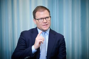 Ein Mann hebt beim Sprechen seinen rechten Zeigefinger in dioe Höhe