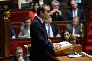 Ein Mann steht an einem Rednerpult und spricht zu anderen Personen