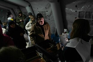 Menschen stehen in einem dunklen Wärmezelt für heiße Suppe an Menschen stehen in einem dunklen Wärmezelt für heiße Suppe an