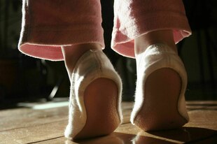 Eine Person mit Turnschläppchen steht auf Zehenspitzen