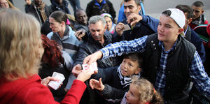 Flüchtlinge nehmen in Mechernich (NRW) vor der Lebensmittelausgabe bei der Tafel Nummernkarten entgegen.