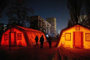 Zelt mit zwei Personen davor, es leuchtet rot Zelt mit zwei Personen davor, es leuchtet rot