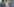 Ein Bundeswehrabzeichen an einer Tarnjacke ist scharf zu sehen, außer Fokus ist ein Mann, der im Hintergrund steht