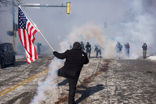 Demonstrant mit Fahne im Tränengasnebel