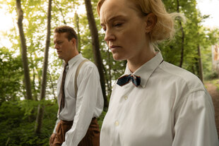 Eine Frau und ein Mann in weißen Hemden gehen unter Bäumen. Eine Frau und ein Mann in weißen Hemden gehen unter Bäumen.