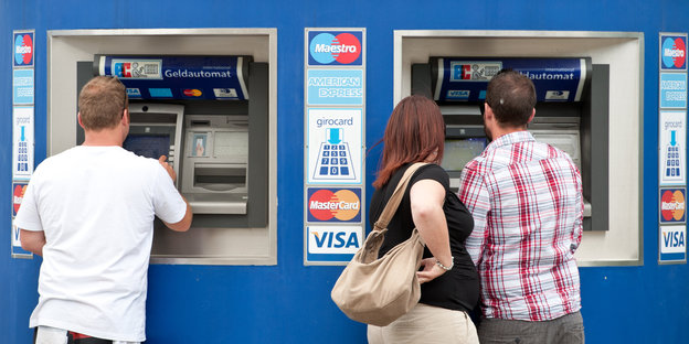 Kunden stehen an einem Geldautomaten.