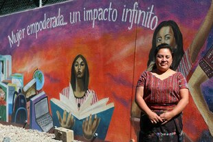 Direktorin Vilma Saloj steht vor der Schule von und für Maya-Frauen, auf der Wand hinter ihr steht auf Spanisch: „Gestärkte Frau – unendliche Wirkung“