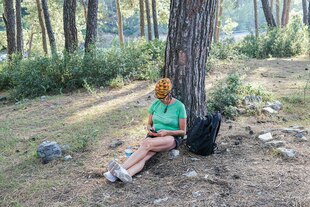 Eine Frau sitzt unter einem Baum im Schatten Eine Frau sitzt unter einem Baum im Schatten