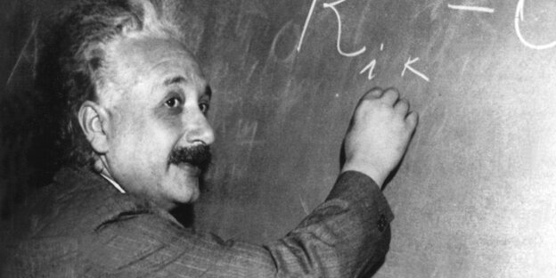 Albert Einstein schreibt mit Kreide Formeln an eine Tafel
