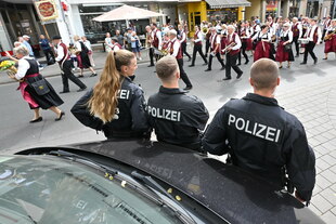 eine Schützengruppe zeieht mit Blechblasinstrumenten an Polizist:innen vorbei