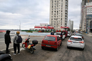 Menschen warten in langen Schlangen an einer Tankstelle