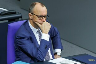 Friedrich Merz stützt seinen Kopf in die Hand, er sitzt auf seinem Platz im Deutschen Bundestag.