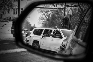 Vermummte Personen gestikulieren aus einem Auto heraus