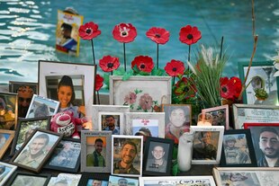 Viele Bilderrahmen mit Porträtfotos stehen am Rand eines Brunnens