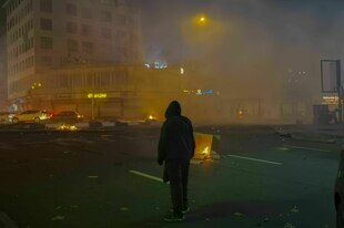 Eine Person steht in einer brennenden Stadtlandschaft