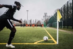 Ein schwarzer Fußballspieler tritt gerade einen Eckball Ein schwarzer Fußballspieler tritt gerade einen Eckball