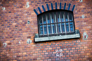 Vergittertes Gefängnisfenster in einer Ziegelmauer