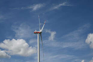 Ein Windrad vor blauem Himmel mit Wolken Ein Windrad vor blauem Himmel mit Wolken