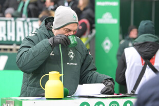 Ein Mann in grüner Daunenjacke trinkt Tee aus einer grünen Werder Bremen Tasse