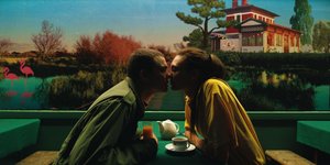 Mann und Frau an einem Tisch in einem Restaurant küssen sich.