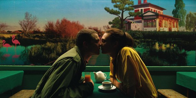 Mann und Frau an einem Tisch in einem Restaurant küssen sich.