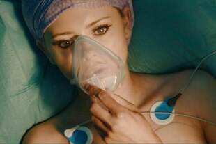 Eine Person liegt mit Beatmungsmaske auf einem OP-Tisch Eine Person liegt mit Beatmungsmaske auf einem OP-Tisch