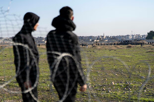 2 Menschen an einer Grenzanlage mit Stacheldraht