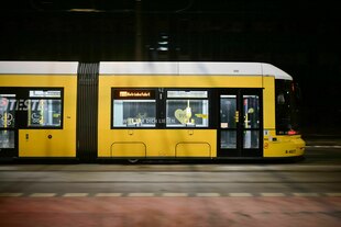 Eine leere Tram fährt in der Dunkelheit Berlins