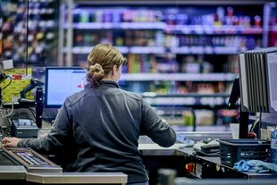 Rückenansicht einer Kassiererin an der Supermarktkasse