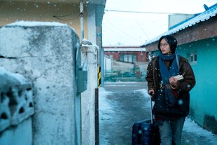 Bella Kim steht mit Büchern in der Hand auf einer winterlichen Straße.