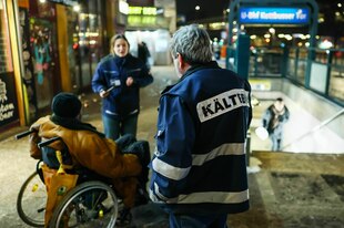 Drei Personen unterhalten sich in der Nähe eines U-Bahneingangs