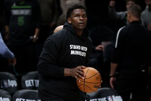 Ein Basketballspieler hält einen Ball in den Händen und trägt einen Sweater mit der Aufschrift "Stand with Minnesota"